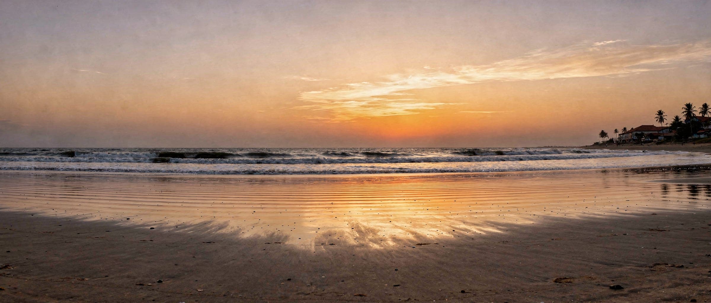 The shoreline at dusk: an orange and violet sky over a dark sea, the wet sand mirroring the colour.