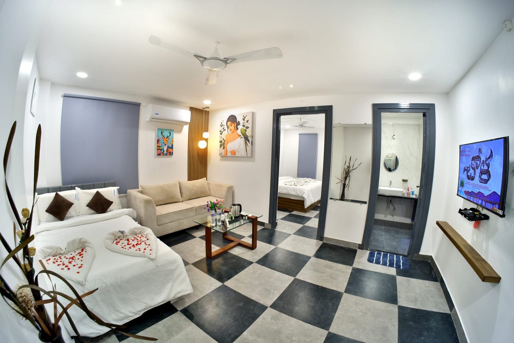 The living area of a Suite Cottage with its second bed made up beside the sofa, and doorways through to the main bedroom and a marble washroom.