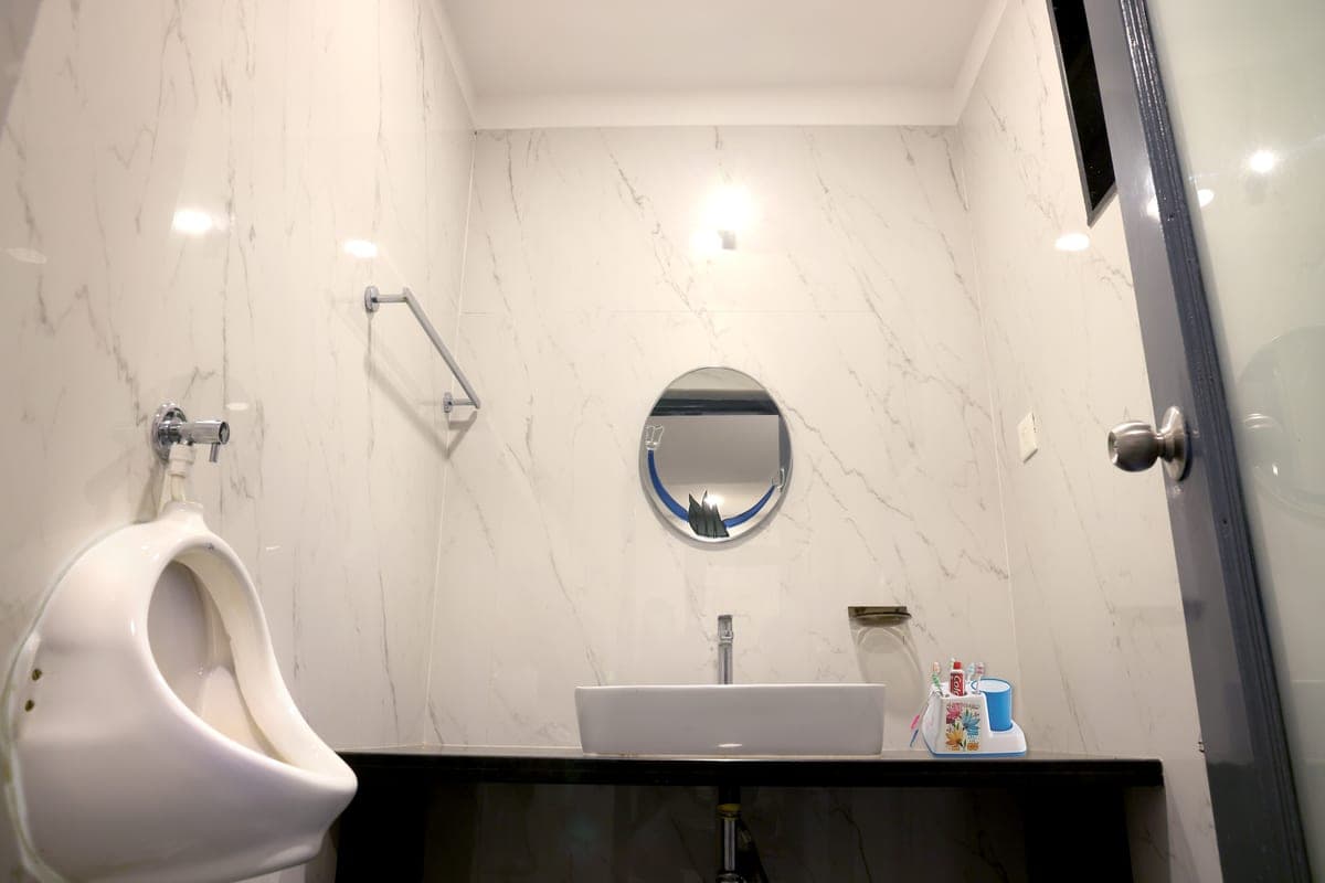 The second washroom in every cottage: a marble-lined vanity with a counter-top basin, round mirror and urinal.