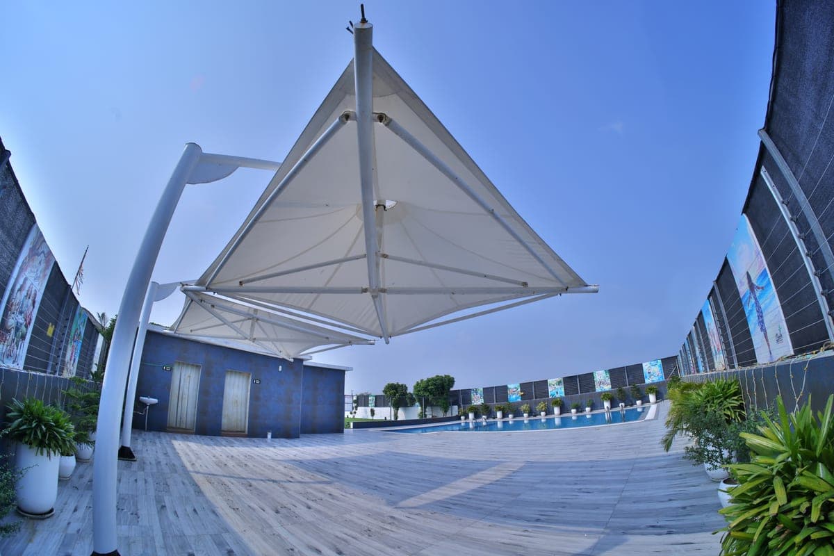 The tensile shade canopy over the pool deck, planters along the far edge.