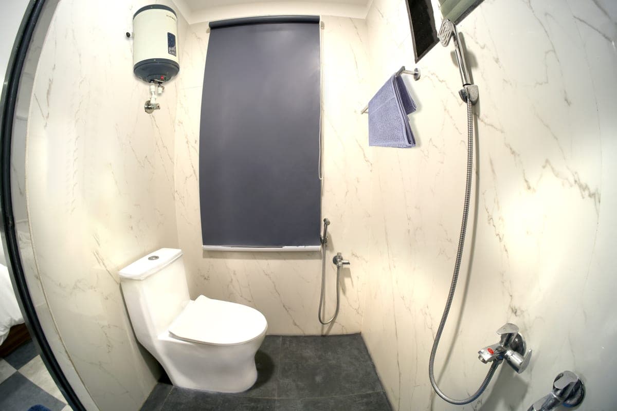 One of the two washrooms in every cottage: a marble-lined shower area with a wall-mounted water heater and a WC.